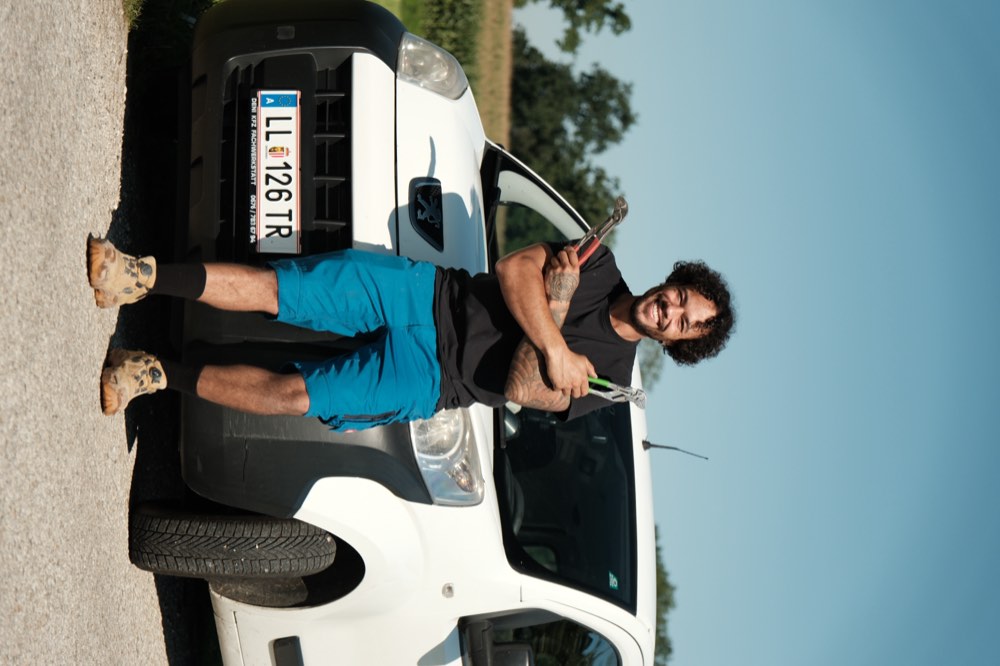 Patrick Raml mit zwei Wasserpumpenzangen vor dem Firmenfahrzeug